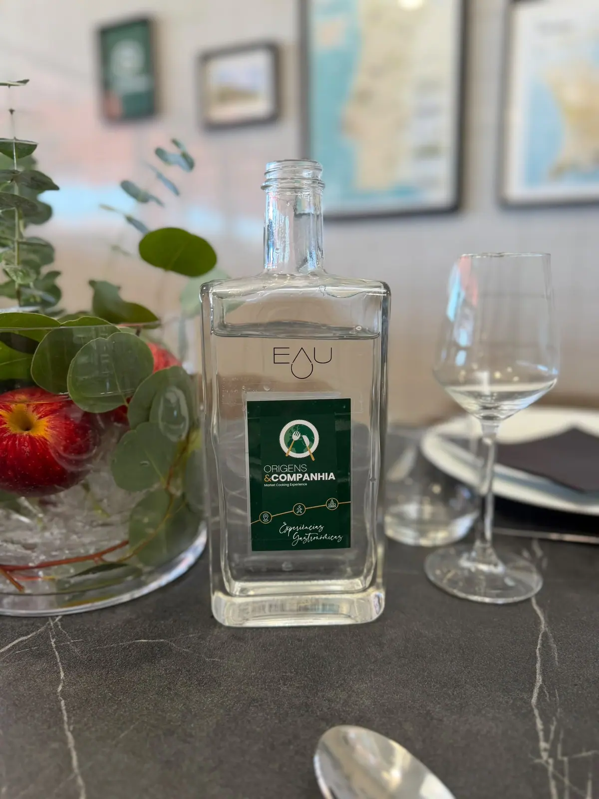 Origens & Companhia branded water bottle on a marble table