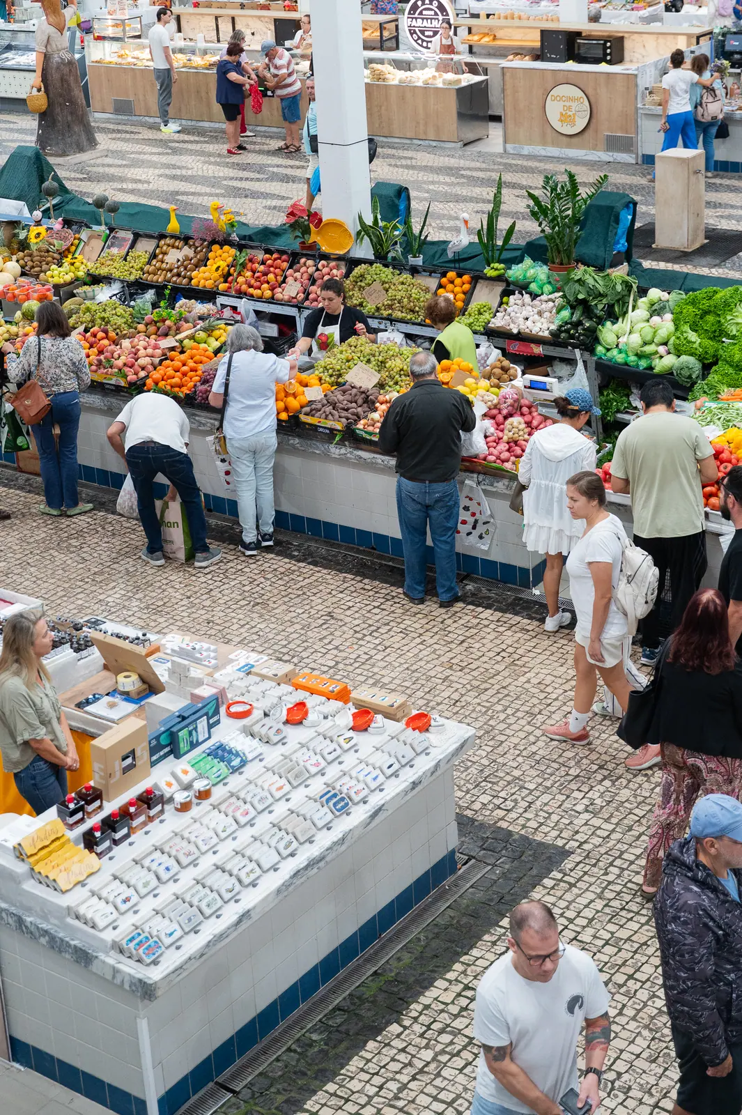Shoppers at fruit, vegetable and tinned fish stalls seen from above