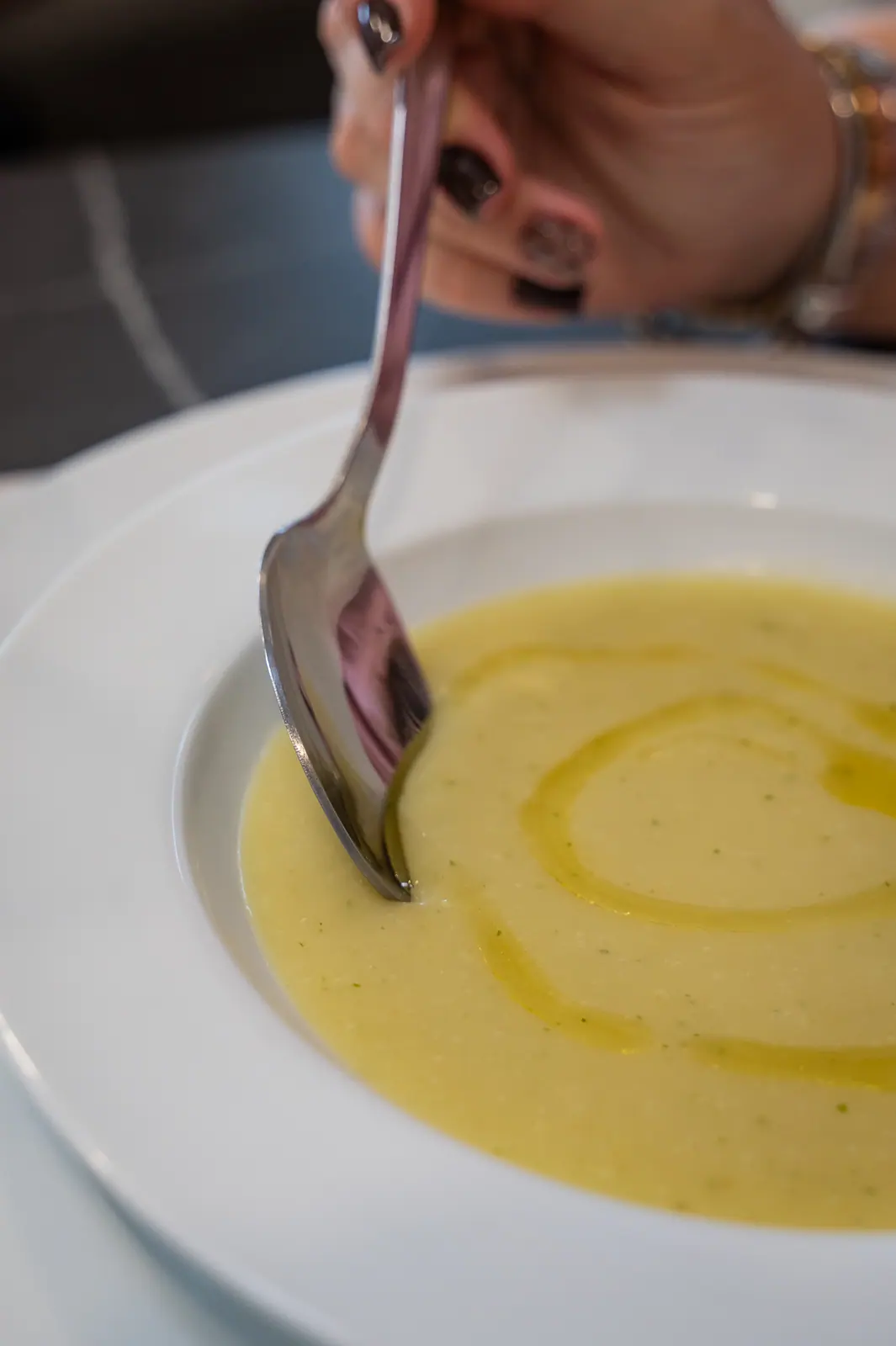 Creamy soup with a swirl of olive oil and a spoon