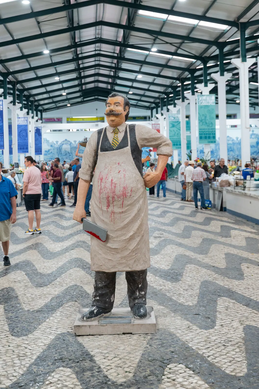 Butcher statue in the market hall on Portuguese wave-pattern pavement