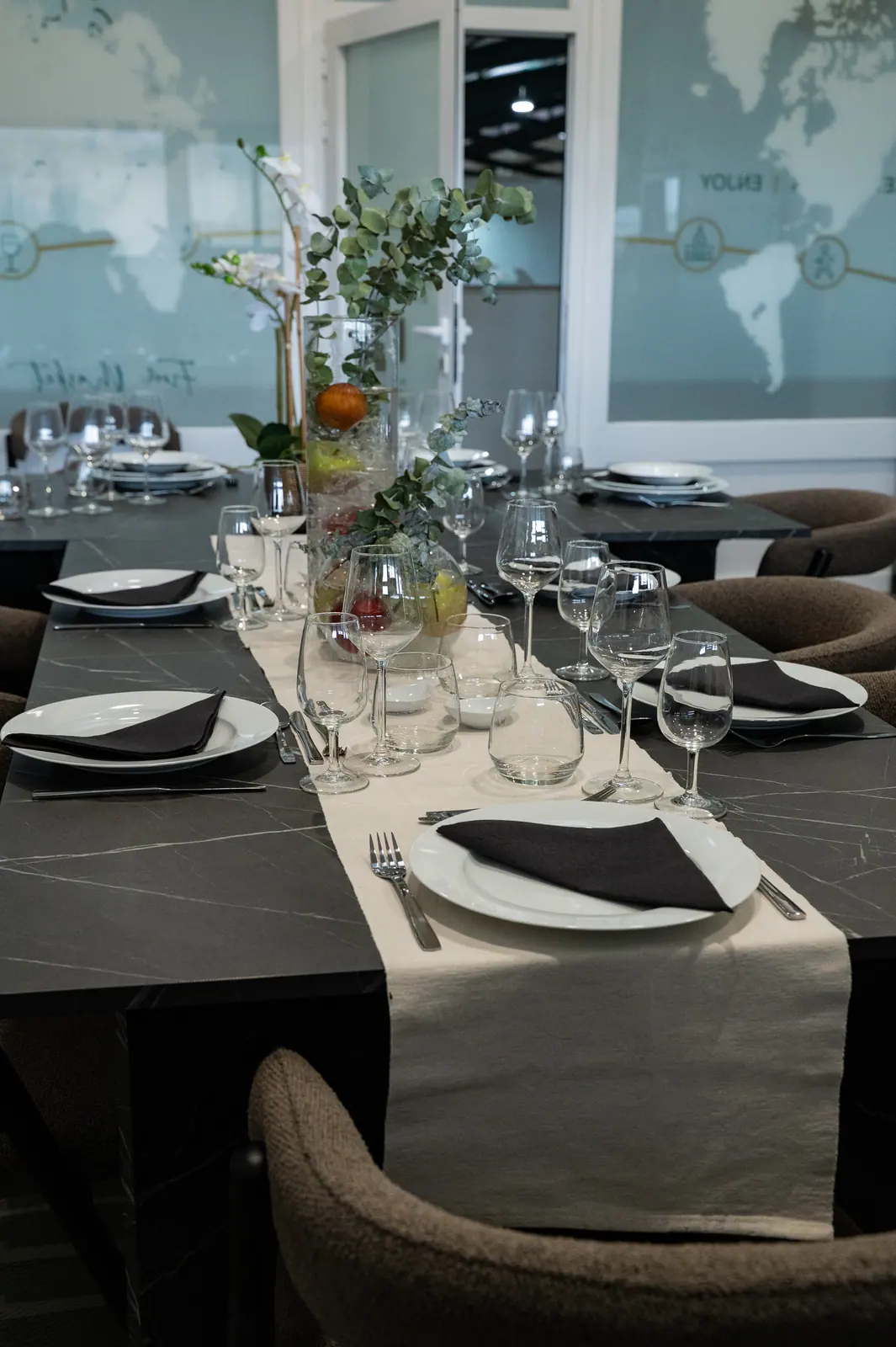 Long dining table set with plates, glasses and eucalyptus centrepiece